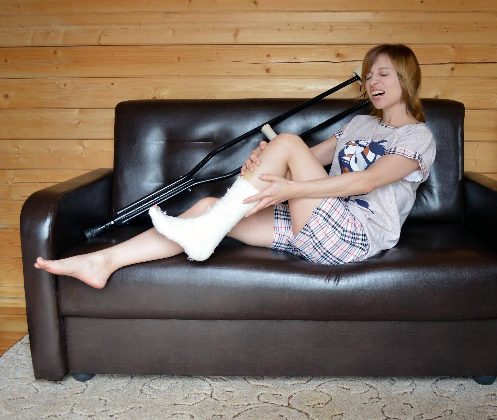A woman sits on a leather sofa and holds her left leg which is in a cast because she hurt it in an incident covered by  ecommerce sales insurance