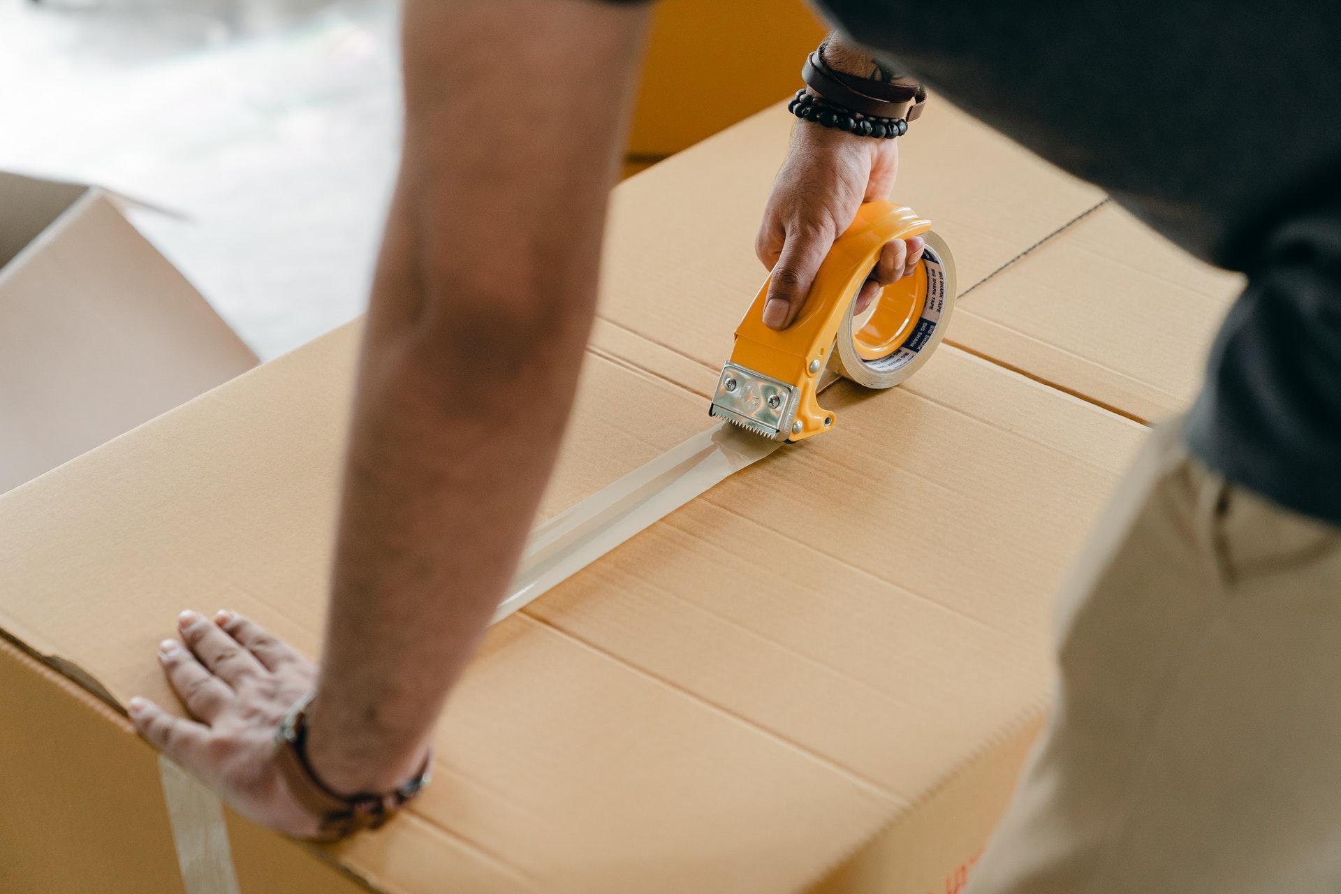 A man taping up an ecommerce order to be shipped to customers.