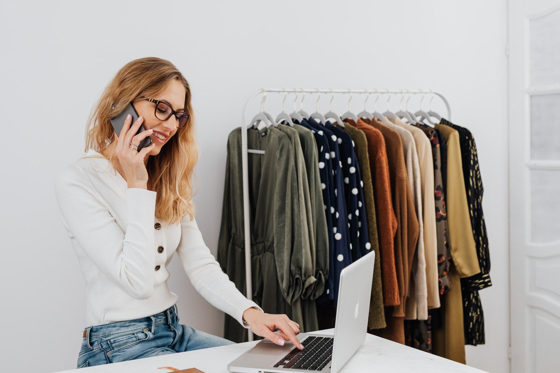 Woman on the phone at a table with a computer dealing with online orders from a Shopify alternative.