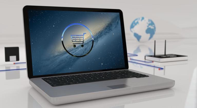 A laptop with an image of ecommerce shopping trolly used as the screensaver while the business owner ponders their ecommerce logistics strategy
