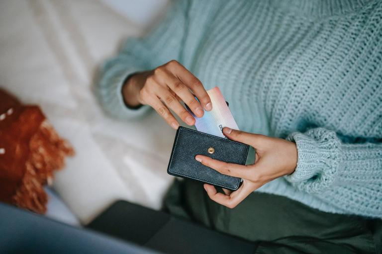 Someone putting a bank card back into their wallet after ordering stock from a supplier with an MOQ.