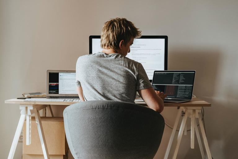 Person sat at a desk with a computer researching Squarespace vs Wix.